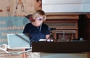 Eine Frau spricht bei einer Tagung im KEH Krankenhaus Berlin. Sie steht hinter einem Pult und hält eine Rede.