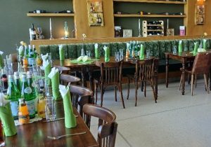 Ein Restaurant mit grünen Tischdecken, Servietten und Flaschen, die eine harmonische und frische Atmosphäre schaffen.